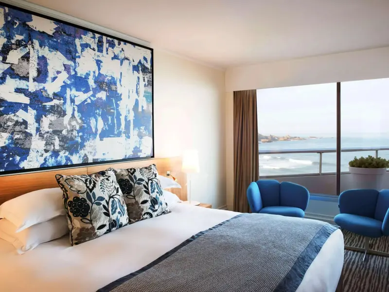Une chambre lumineuse avec un grand lit et une vue sur la mer.