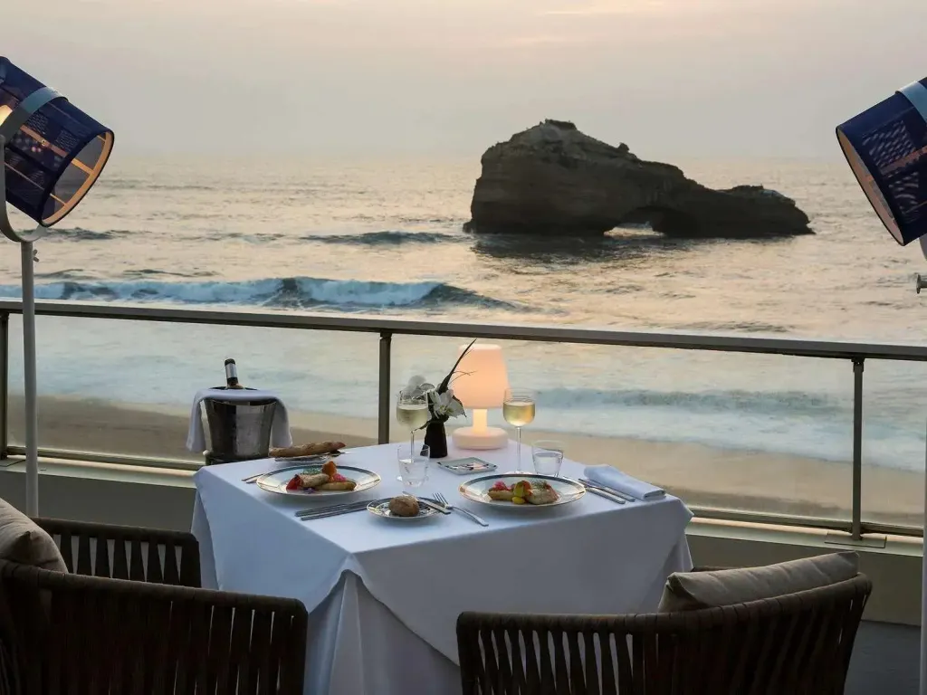 Une table dressée pour deux personnes en extérieur avec vue sur la mer.