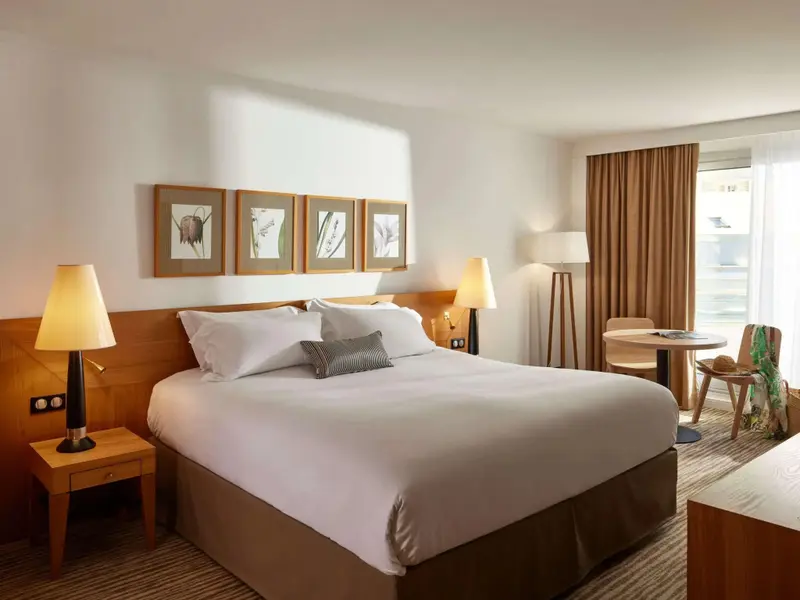 Une chambre lumineuse avec un grand lit et un coin salon.