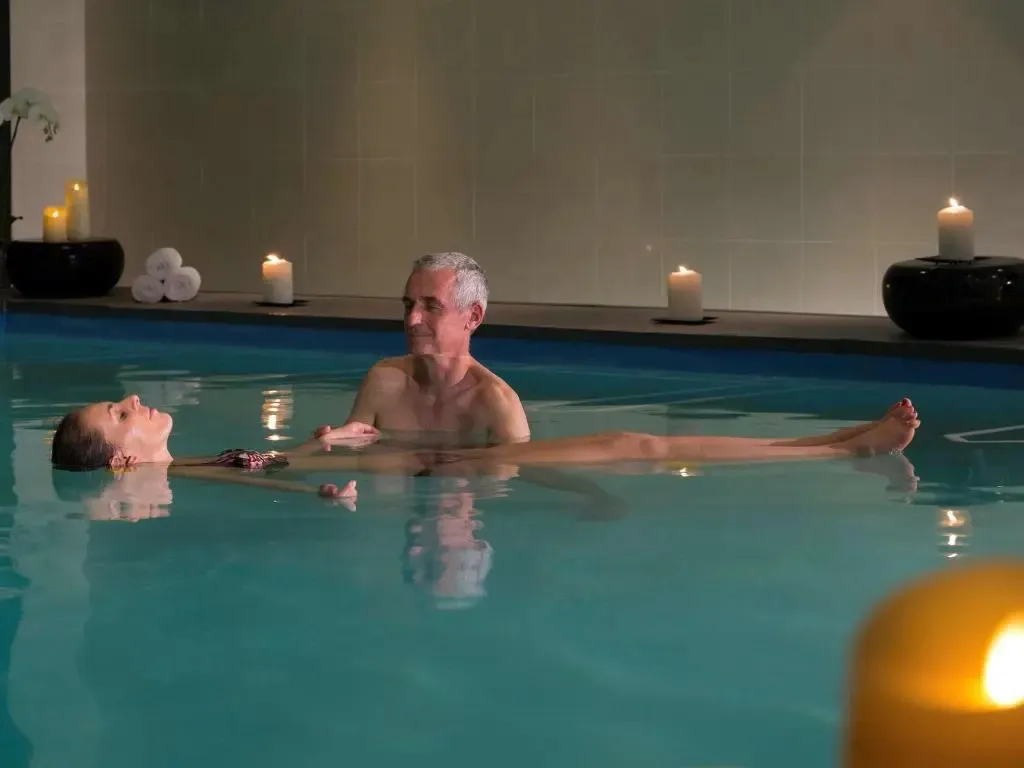 Un couple se détend dans une piscine intérieure éclairée aux bougies.