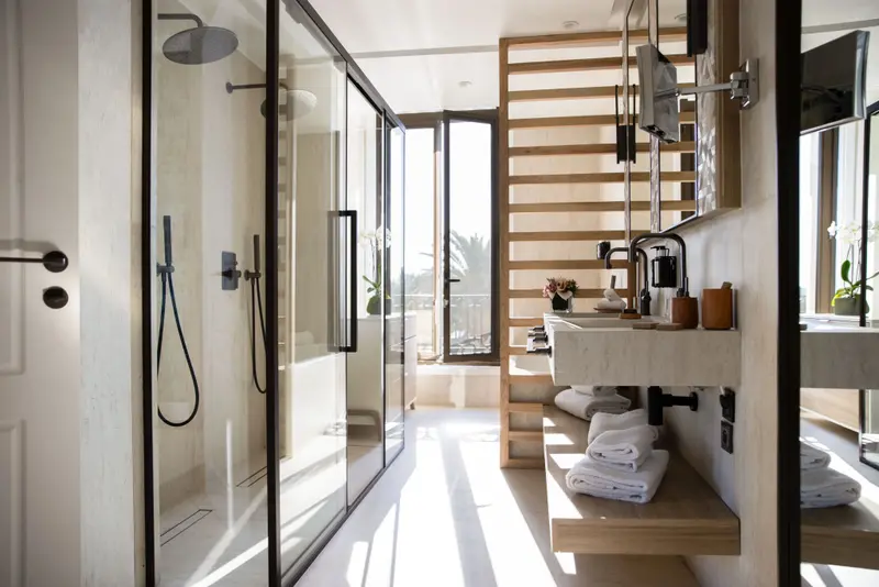Une salle de bain lumineuse avec une douche vitrée et un plan vasque en marbre.