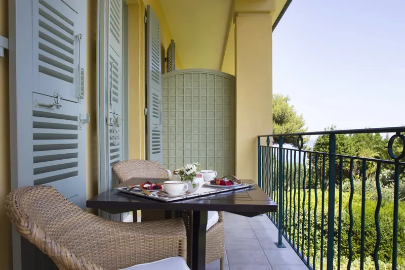 Une table est dressée pour le petit-déjeuner sur un balcon ensoleillé.