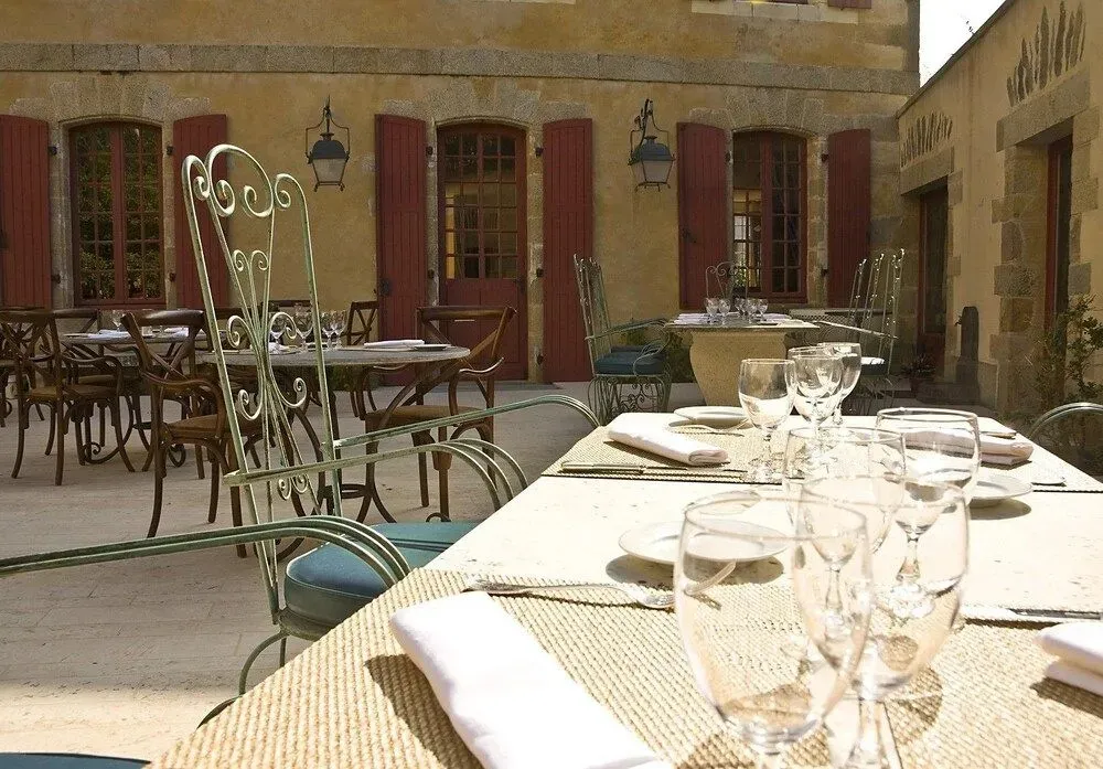 Tables dressées en terrasse devant un bâtiment en pierre.