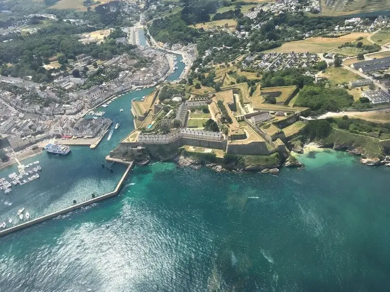 Vue aérienne d'une côte rocheuse avec un fort et une ville portuaire.