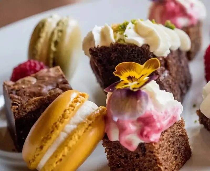 Assortiment de pâtisseries colorées et décorées sur une assiette blanche.
