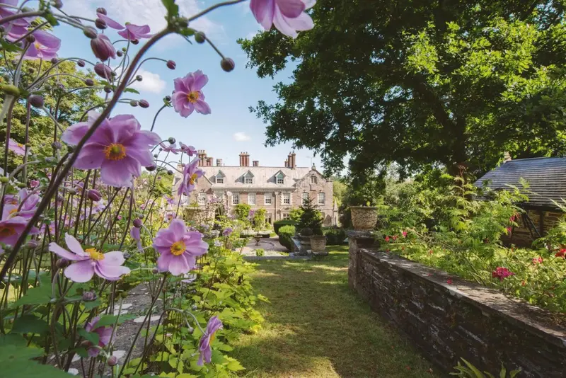 Un jardin fleuri mène vers une façade de bâtiment classique.