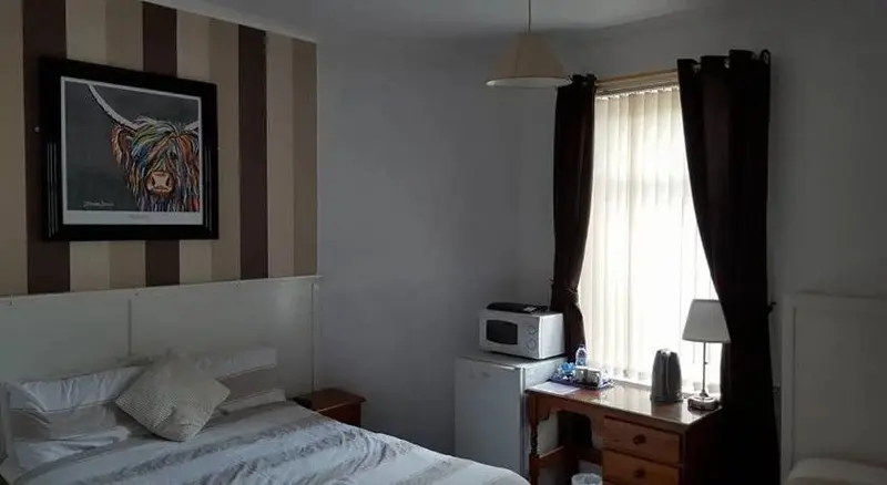 Une chambre à coucher avec un lit et un bureau près d'une fenêtre.