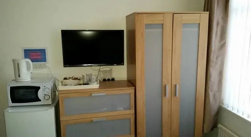 Une télévision est fixée au mur au-dessus d'un meuble en bois.