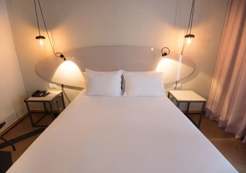 Une chambre lumineuse avec un grand lit blanc et des tables de chevet.