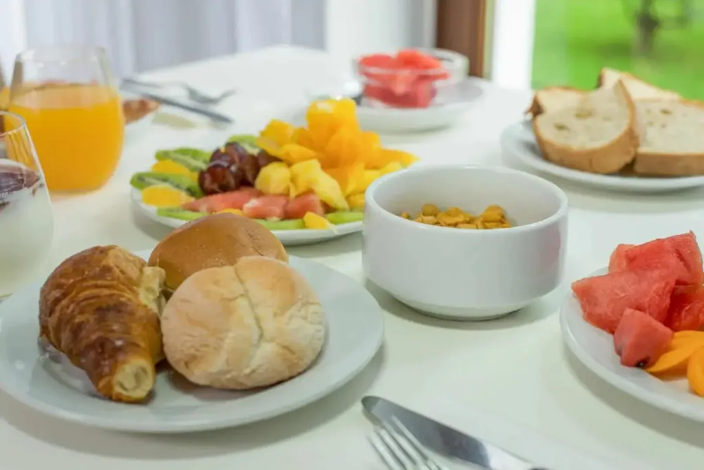 Une table est dressée avec des viennoiseries, des fruits et des céréales.