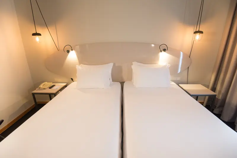 Deux lits simples dans une chambre lumineuse et minimaliste.