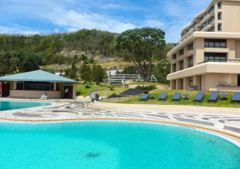 Piscine turquoise bordée d'une mosaïque et d'un espace de détente avec transats.