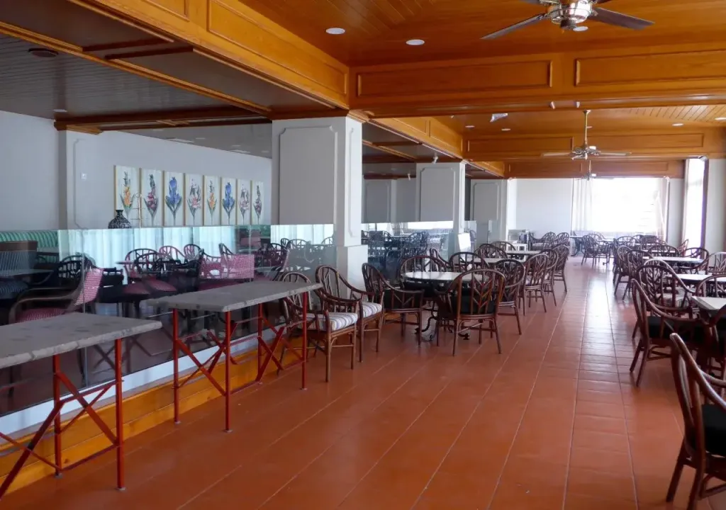 Une grande salle lumineuse est aménagée avec des tables et des chaises.