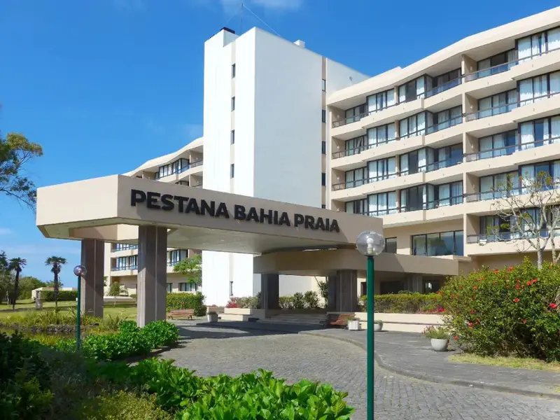 Façade d'un bâtiment moderne avec une entrée ombragée et des espaces verts.