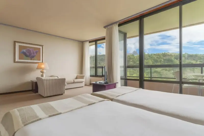 Une chambre lumineuse avec un coin salon et une vue sur la végétation.
