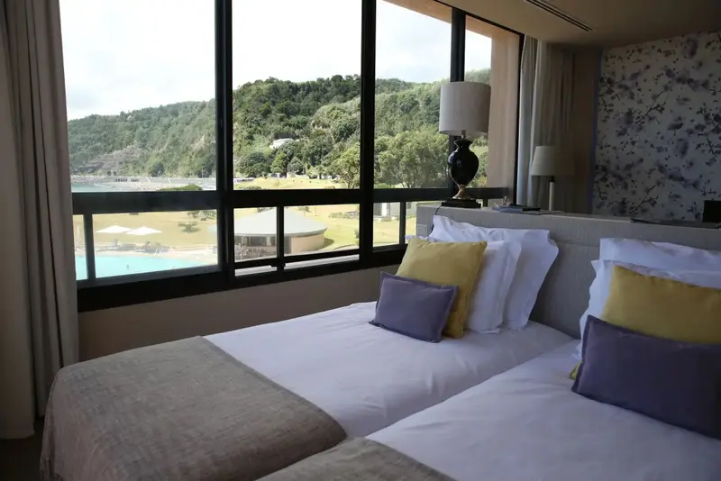 Une chambre lumineuse avec un grand lit et une vue sur un paysage verdoyant.