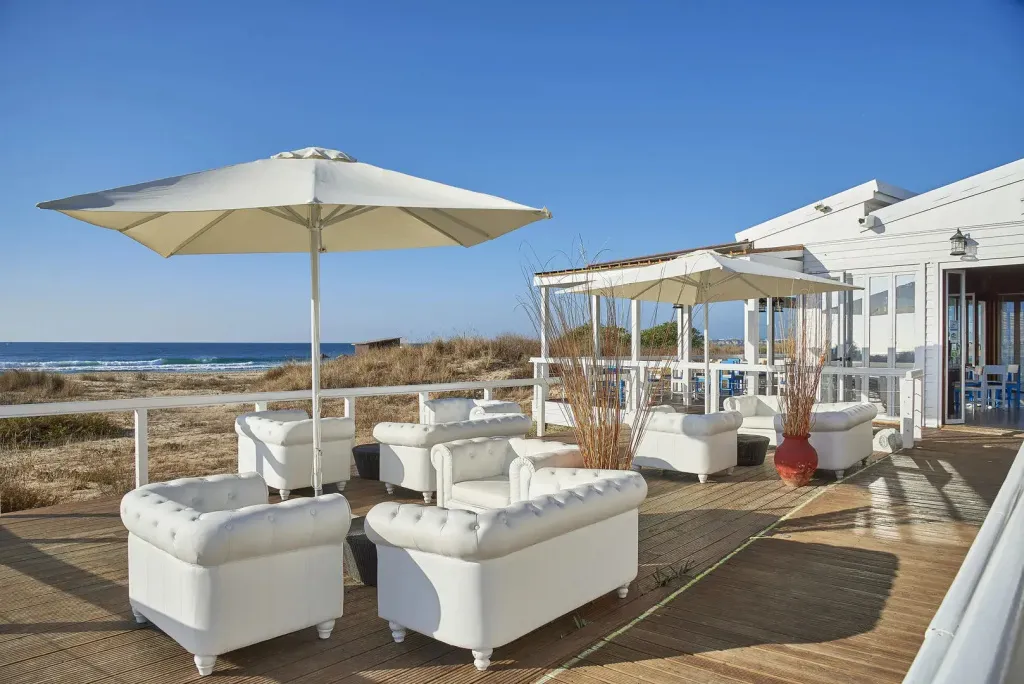 Espace de détente extérieur avec mobilier blanc et vue sur la mer.