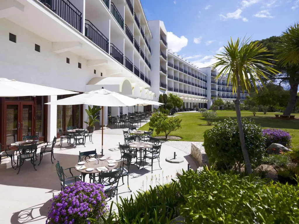 Une terrasse ombragée avec des tables et des chaises invite à la détente dans un cadre verdoyant.
