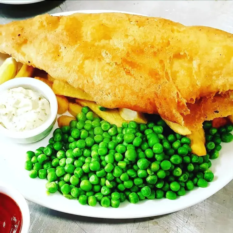 Assiette généreuse de fish and chips avec une portion de petits pois.