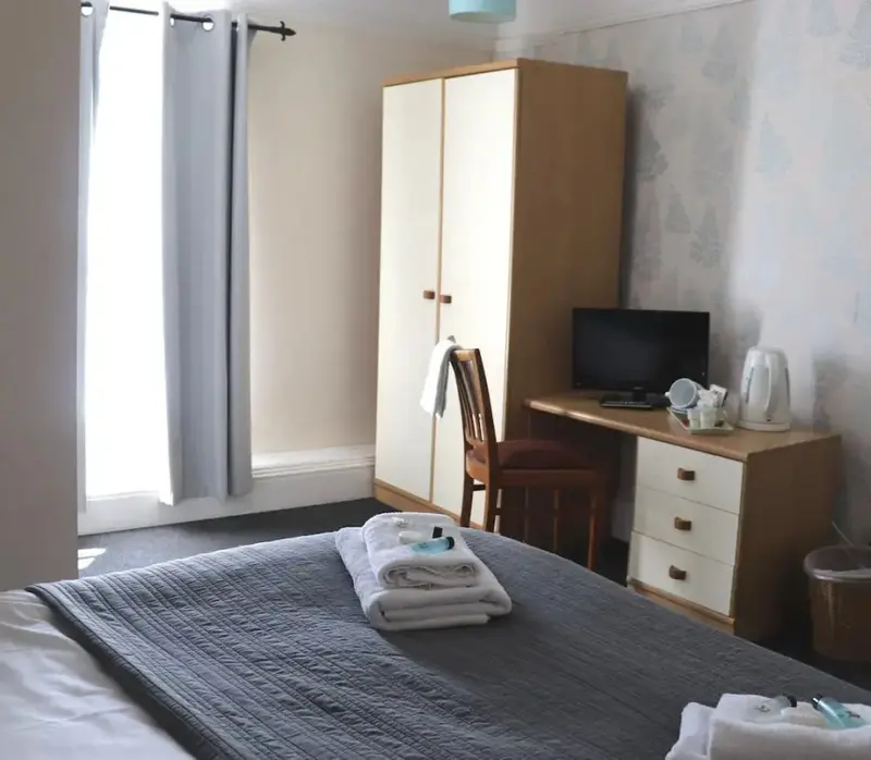 Une chambre lumineuse avec un lit fait et un bureau.