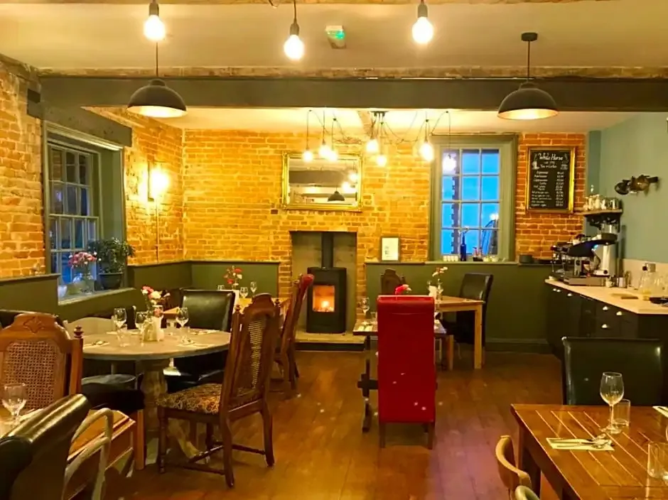 Une salle de restaurant chaleureuse avec des tables dressées et une cheminée.