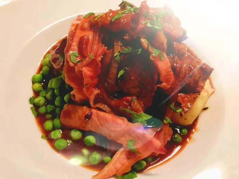 Assiette de viande rouge accompagnée de légumes verts et d'une sauce foncée.