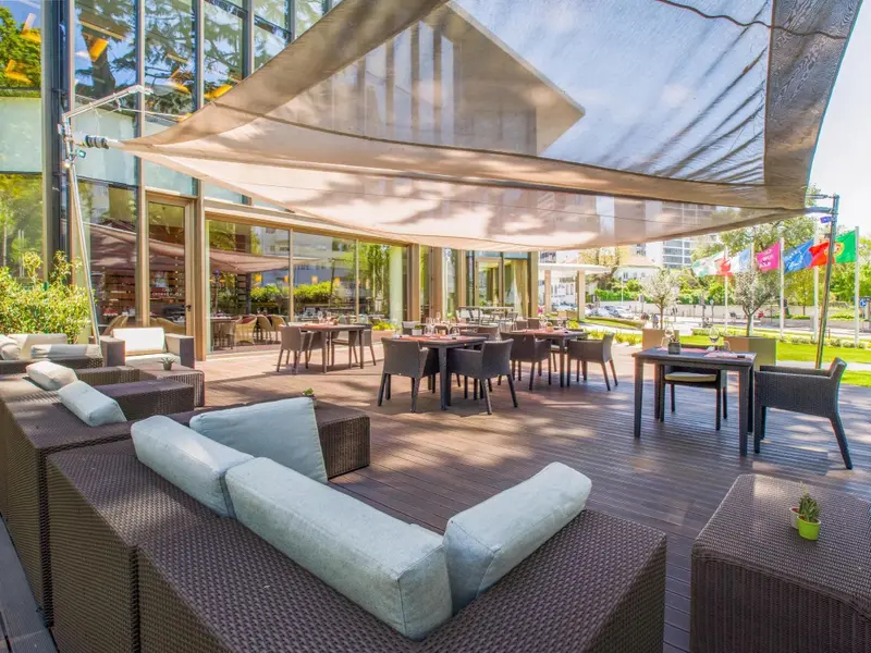 Espace de détente extérieur avec mobilier confortable et tables de repas ombragées.
