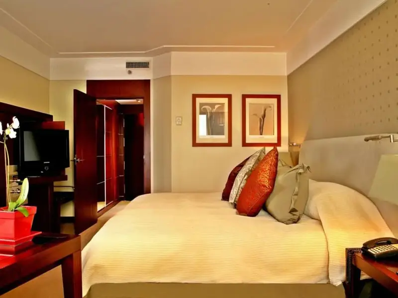 Une chambre lumineuse avec un grand lit et des tableaux décoratifs.