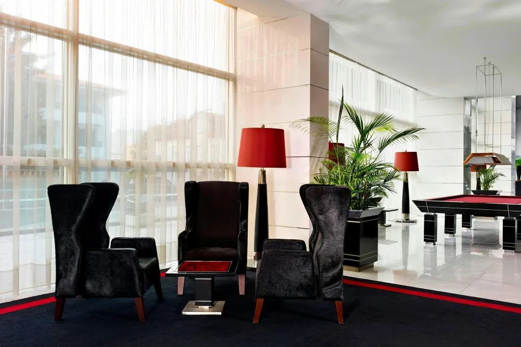 Espace de détente avec des fauteuils et des lampes sur fond de baies vitrées.