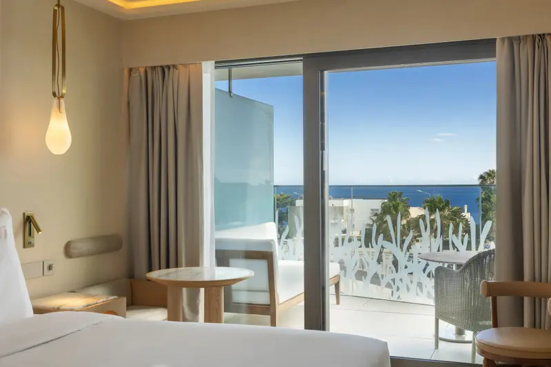 Une chambre lumineuse s'ouvre sur une terrasse avec vue sur la mer.