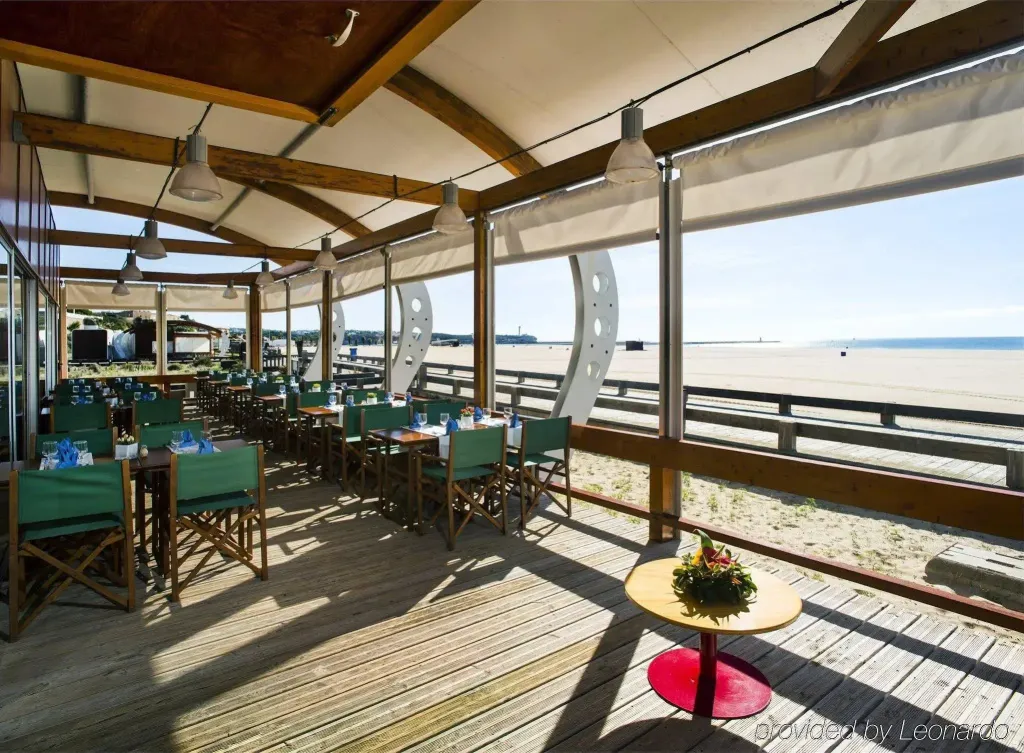 Une salle à manger lumineuse s'ouvre sur une plage de sable.