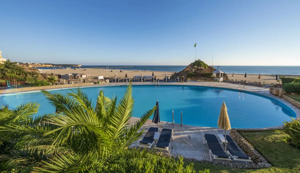 Une piscine d'hôtel avec des transats et une vue sur la plage.