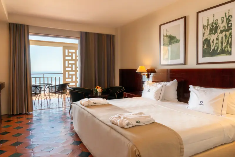 Une chambre lumineuse avec un lit blanc et une vue sur la mer.