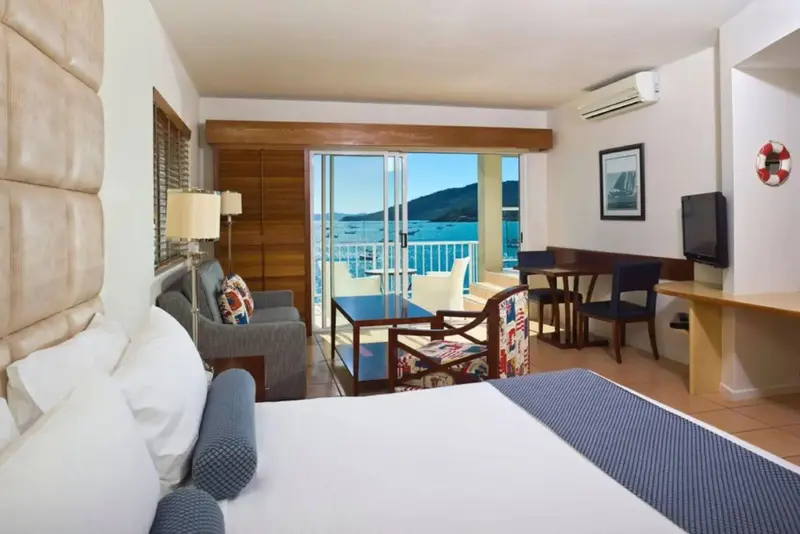 Une chambre lumineuse avec un coin salon et une vue sur la mer.