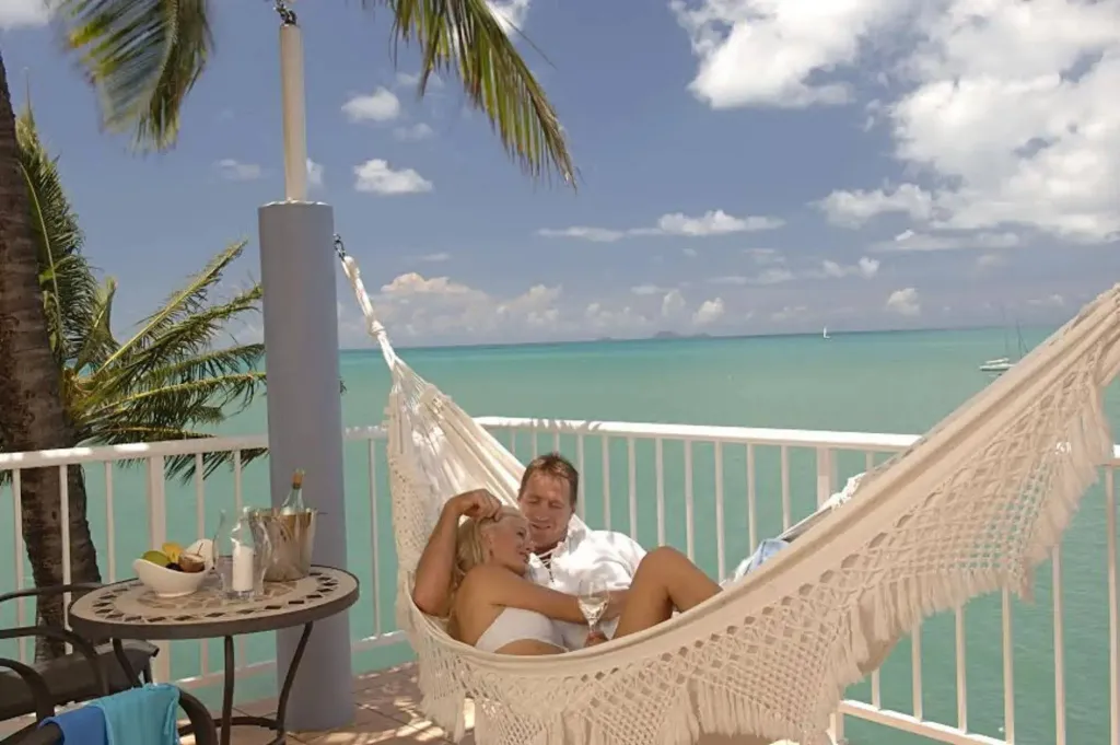 Un couple se détend dans un hamac sur une terrasse avec vue sur la mer.