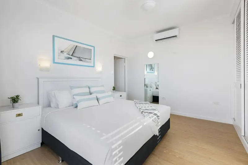Une chambre lumineuse avec un grand lit recouvert de linge blanc.