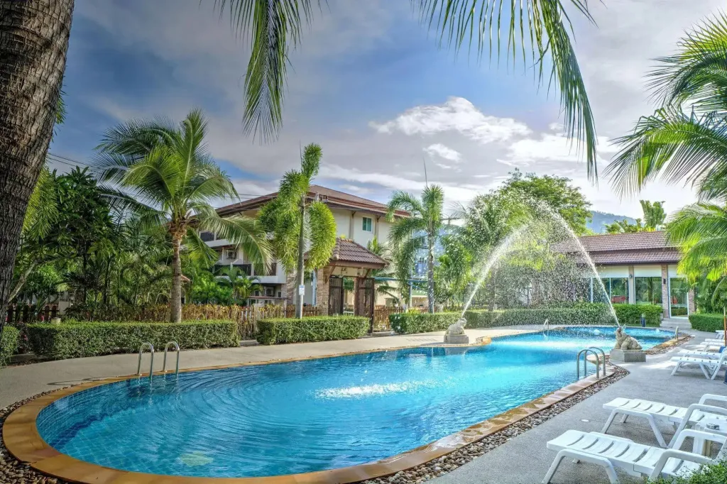 Une piscine extérieure avec fontaine et transats dans un cadre tropical.