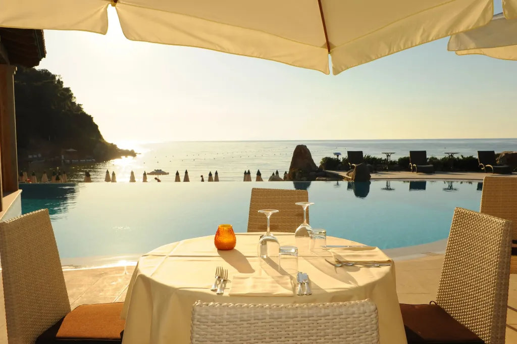 Une table est dressée en bord de piscine avec vue sur la mer.