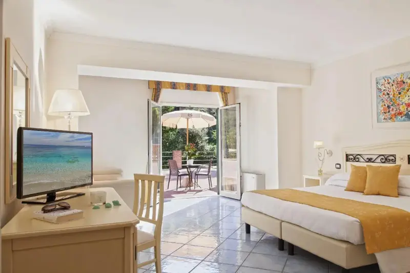 Une chambre lumineuse s'ouvre sur une terrasse avec mobilier de jardin.