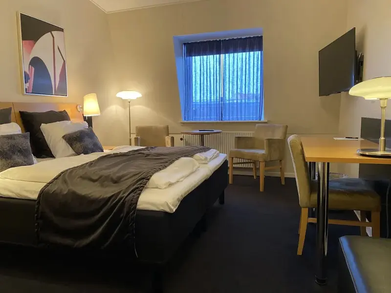 Une chambre d'hôtel lumineuse avec un grand lit et un espace bureau.