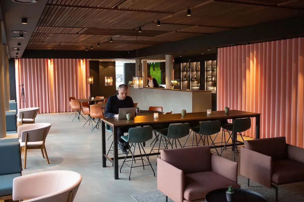 Un homme est assis à une table, travaillant sur un ordinateur portable dans un espace lumineux et moderne.