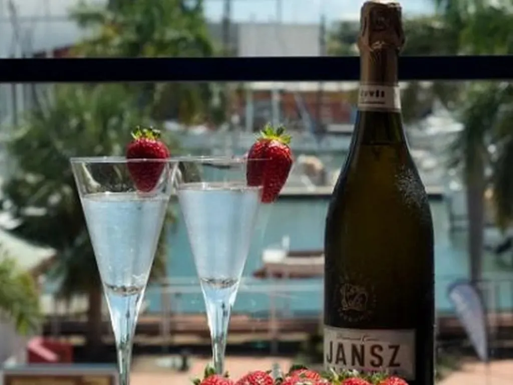 Deux coupes de champagne et une bouteille de vin blanc sont présentées avec des fraises.