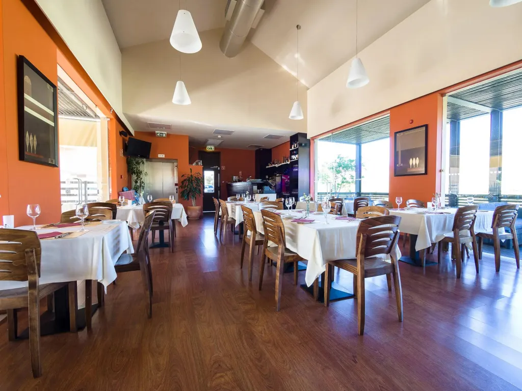 Une salle lumineuse avec des tables dressées pour un repas.