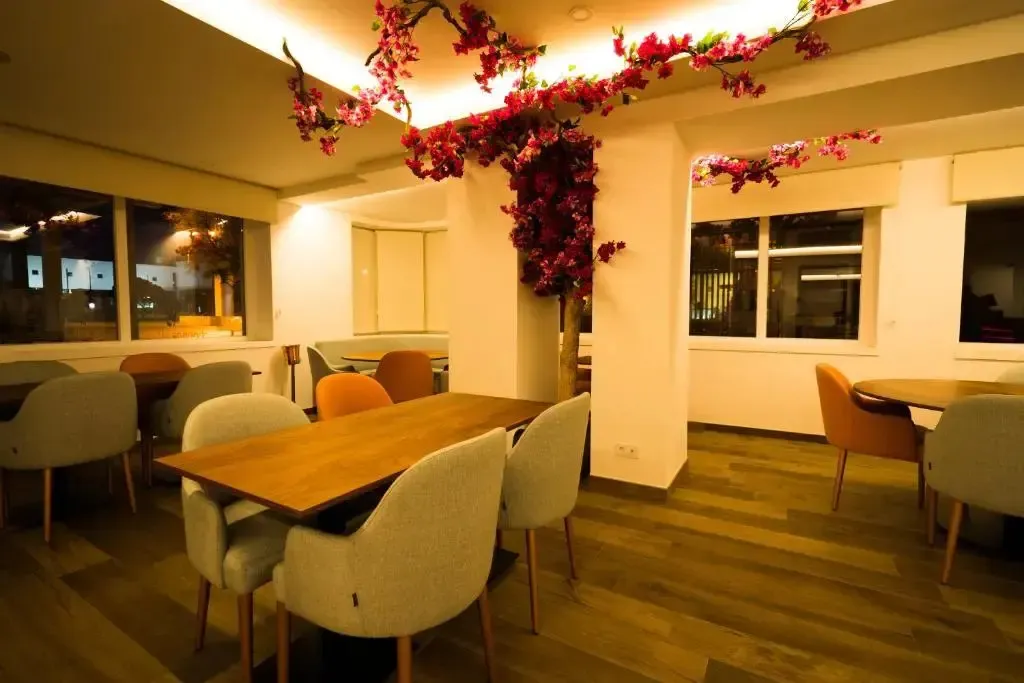 Une salle lumineuse avec des tables et des chaises est décorée de fleurs artificielles.