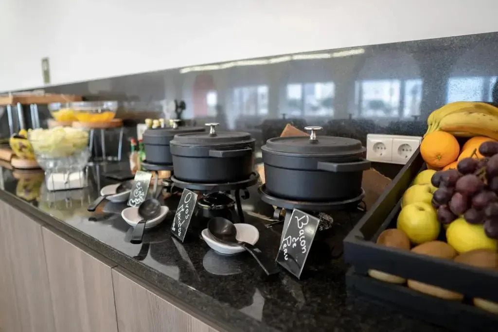 Un buffet propose des fruits frais et des plats chauds dans un espace lumineux.