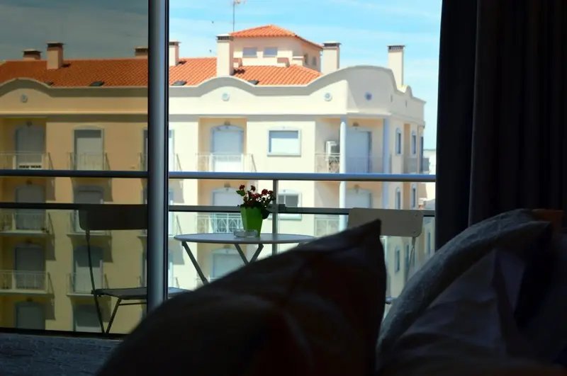Une table et des chaises se trouvent sur un balcon avec vue sur des bâtiments.