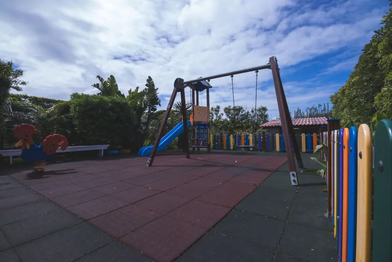 Espace de jeux coloré avec balançoire et toboggan sur sol amortissant.