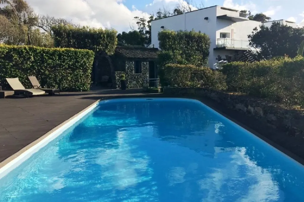 Une piscine rectangulaire avec deux transats sur le bord.