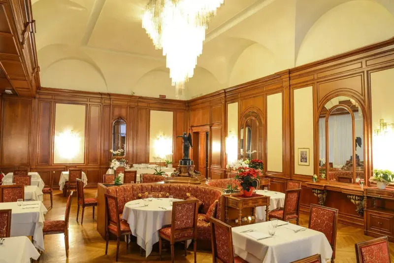 Une salle à manger élégante avec des tables dressées et un grand lustre.