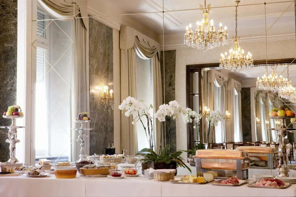 Un buffet de nourriture est présenté sur une table recouverte d'une nappe blanche dans une salle lumineuse.